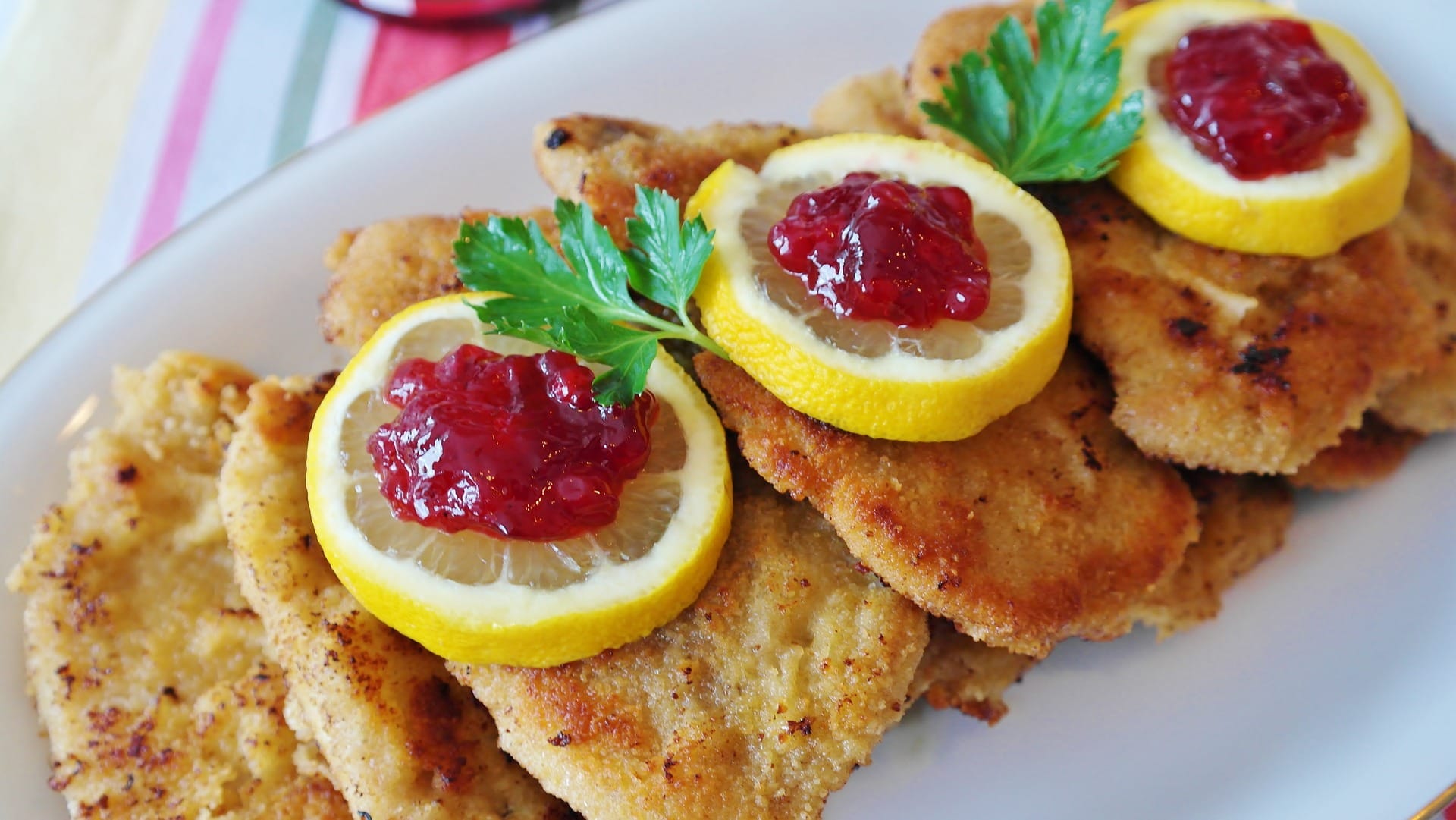 Mehrere Schnitzel mit Zitrone und Preiselbeermarmelade in einem Restaurant aus der Nähe