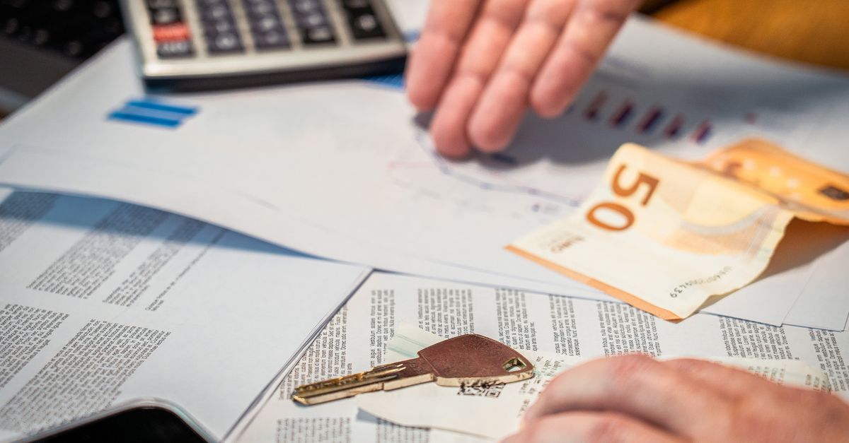 Hände prüfen Unterlagen, einen 50-Euro-Schein und einen Schlüssel auf einem Tisch.