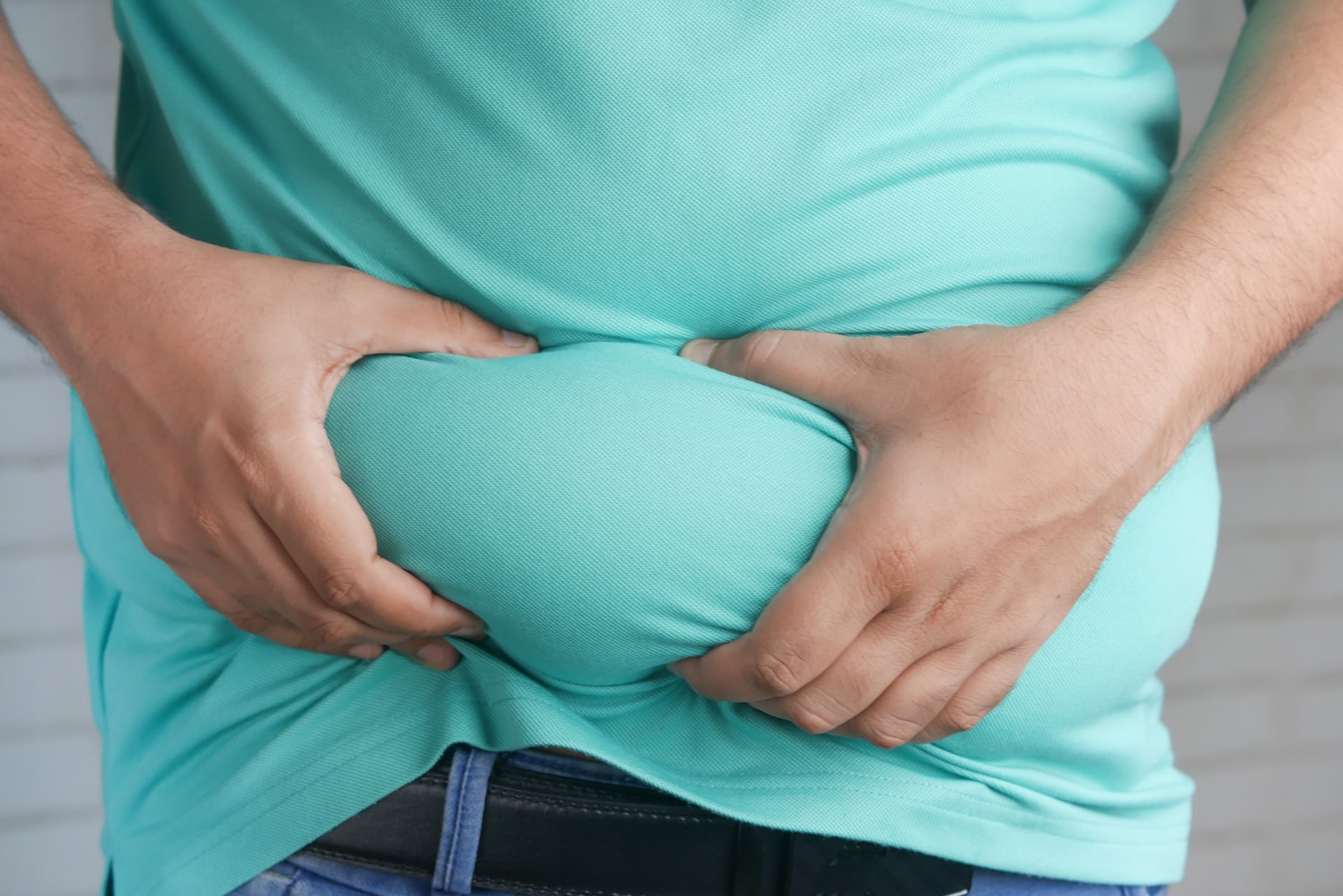 Ein Bauch einer Person die den Speck zwischen den Händen hält